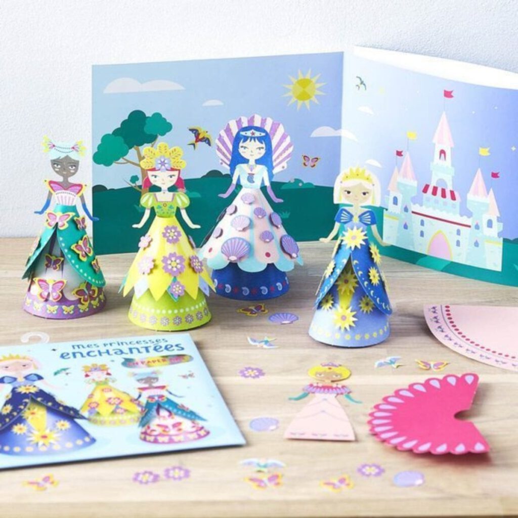 Zestaw do tworzenia papierowych księżniczek z papieru DIY. Kolorowe księżniczki w pięknych sukniach, w tle plansza z zamkiem i pięknym ogrodem.